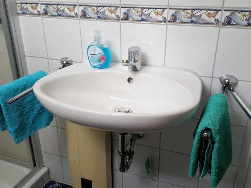 a white sink in a bathroom with blue towels at Ferienwohnung Kunze in Obernsees