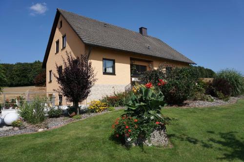 Ein Haus mit einem Blumenstrauß im Hof. in der Unterkunft Ferienwohnung Penning in Oberfellendorf