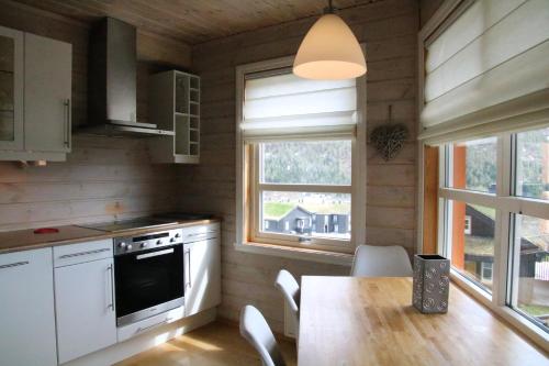 uma cozinha com uma mesa, um fogão e janelas em Myrkdalen Resort Nedre Byggardslii apartment em Vossestrand