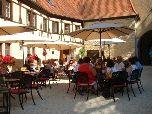 un grupo de personas sentadas en mesas con sombrillas en Burg Katzenstein en Katzenstein