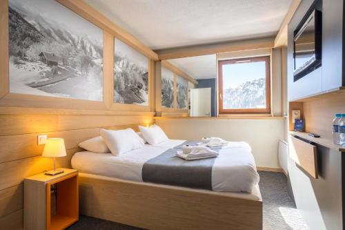 een slaapkamer met een bed in een kamer met een raam bij Hôtel Club mmv Les Brévières **** in Tignes