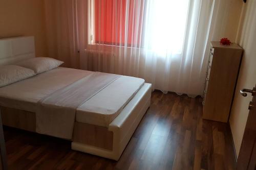 1 dormitorio con 1 cama con ventana y suelo de madera en Apartament Gia, en Oradea