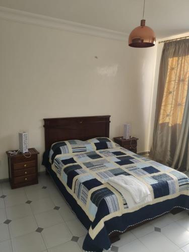a bedroom with a bed with a blue and white comforter at Appartement hyper centre de Tanger (Boulevard Pasteur) in Tangier