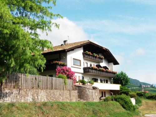 a white house with flowers on a wall at Garni Runggner Traubenhof in Termeno