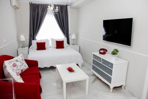サンルーカル・デ・バラメダにあるApartamento Centro Sanlucarのベッドルーム(ベッド1台、テレビ、赤い椅子付)