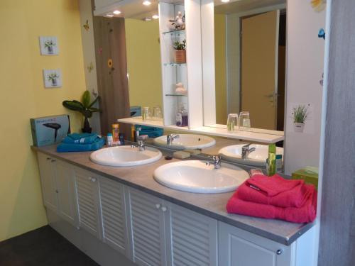 uma casa de banho com 3 lavatórios e um espelho grande em Chez Corinne em La Roche-Chalais