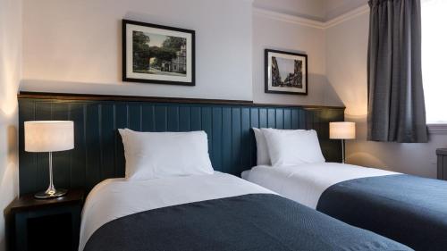 um quarto de hotel com duas camas e duas lâmpadas em Southern Cross em Watford