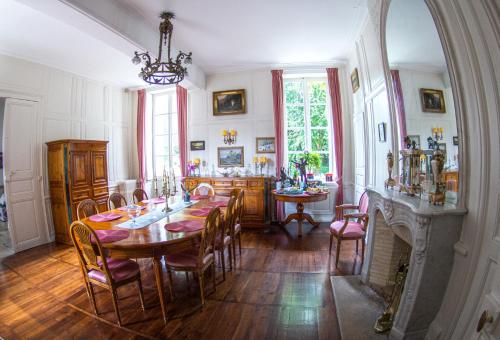 ein Esszimmer mit einem Tisch, Stühlen und einem Kamin in der Unterkunft Saint-Eusèbe Mansion - Hôtel Particulier St-Eusèbe in Auxerre