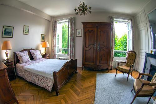 a bedroom with a bed and a dresser and two windows at Saint-Eusèbe Mansion - Hôtel Particulier St-Eusèbe in Auxerre