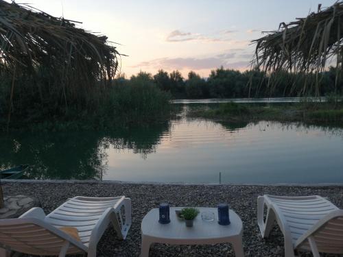 two chairs and a table next to a lake at Skadar Lake House Virpazar in Virpazar