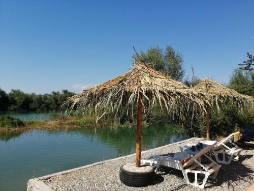 a straw umbrella and a wheelbarrow and a boat with a wheel at Skadar Lake House Virpazar in Virpazar