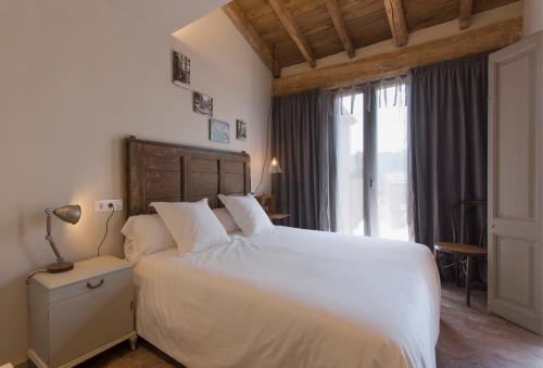 a bedroom with a white bed and a large window at El Jardinet de Sant Esteve in Olot