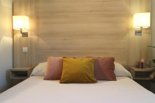 
a bed with a white comforter and pillows at Hôtel d'Orsay in Toulouse
