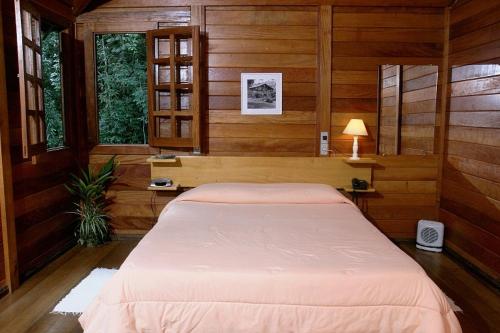 a bedroom with a large bed in a room with wooden walls at Estalagem Fazenda Lazer in Carandaí