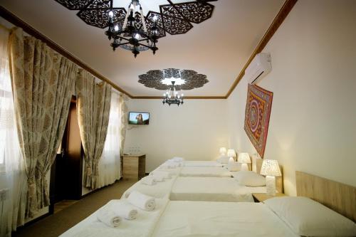 a row of beds in a room with a chandelier at Khalima in Bukhara