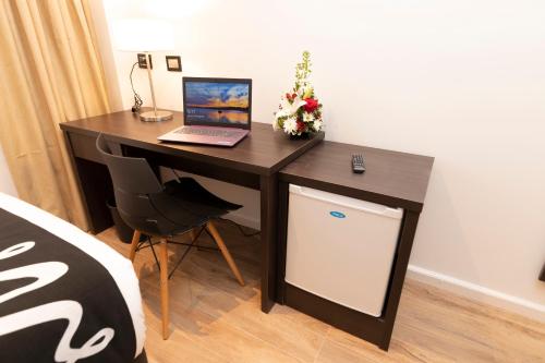 a desk with a laptop and a small refrigerator at Amerian Rafaela Hotel in Rafaela