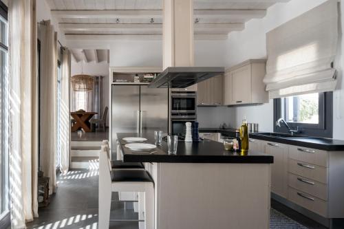 a kitchen with white cabinets and a black counter top at Myconian Platinum Senior Villa in Kalafatis