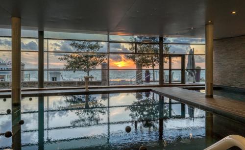 - une piscine reflétant un coucher de soleil dans un bâtiment dans l'établissement Spa Marin Du Val Andre Thalasso Resort, à Pléneuf-Val-André