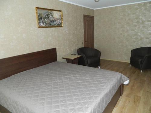 1 Schlafzimmer mit einem Bett und 2 Stühlen in der Unterkunft Соборная улица Апартаменты in Krementschuk