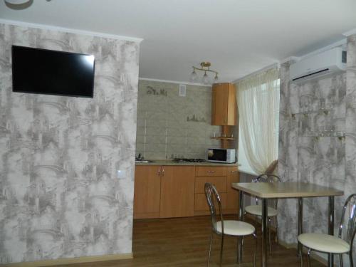 eine Küche mit einem Tisch und einem TV an der Wand in der Unterkunft Соборная улица Апартаменты in Krementschuk