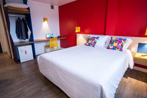 a bedroom with a large white bed with a red wall at ibis Styles Campina Grande in Campina Grande
