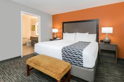 a bedroom with a large white bed with an orange wall at La Quinta by Wyndham Fredericksburg in Fredericksburg