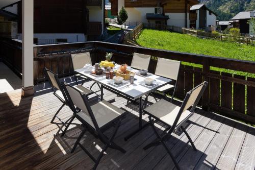 a table and chairs on a deck with food on it at Casa Della Vita by Zermatt Premium Apartments in Zermatt
