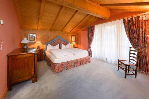 a bedroom with a bed and a chair in a room at Chalet Kisseye with heated Pool and Matterhorn views in Zermatt