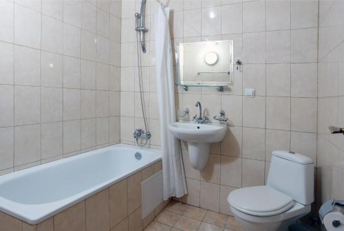 a bathroom with a tub and a toilet and a sink at Acropolis Hotel in Pazardzhik