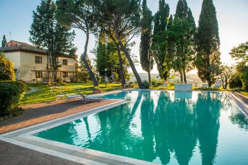 ein Pool in einem Park mit Bäumen und einem Gebäude in der Unterkunft Agriturismo Pieve Sprenna in Buonconvento