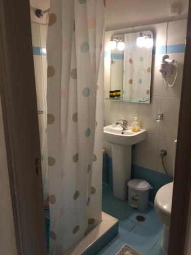 y baño con cortina de ducha y lavamanos. en Gorgona Hotel, en Skála Sykaminéas