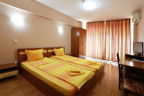 - une chambre dotée d'un grand lit avec des draps jaunes dans l'établissement Acropolis Hotel, à Pazardjik