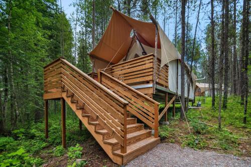 a yurt in the woods with a staircase leading to it at Under Canvas Glacier in Coram