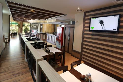 a restaurant with tables and a tv on the wall at Acropolis Hotel in Pazardzhik