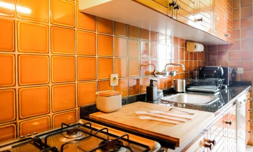 a kitchen with orange tiled walls and a wooden cutting board at Cozy 3 Room Apartment in Penafiel Centre in Penafiel