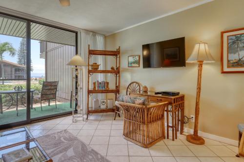 a living room with a desk and a tv and a window at Mahina Surf 109 in Kahana