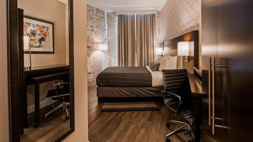 a hotel room with a bed and a desk with a chair at Best Western Plus St. Christopher Hotel in New Orleans