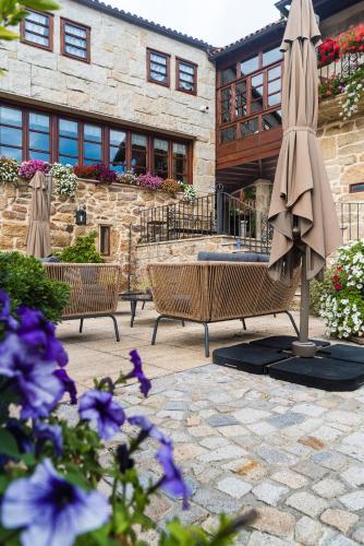 a patio with two chairs and an umbrella and flowers at Pazo de Esposende in Esposende