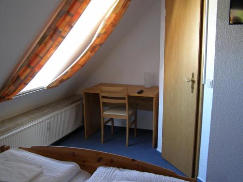 a bedroom with a desk and a bed and a window at Hotel Alt Vinnhorst in Hannover