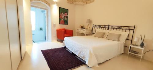 um quarto com uma cama branca e uma cadeira vermelha em Casa Carmela em Ceglie Messapica