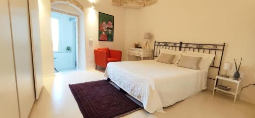 une chambre avec un lit blanc et une chaise rouge dans l'établissement Casa Carmela, à Ceglie Messapica