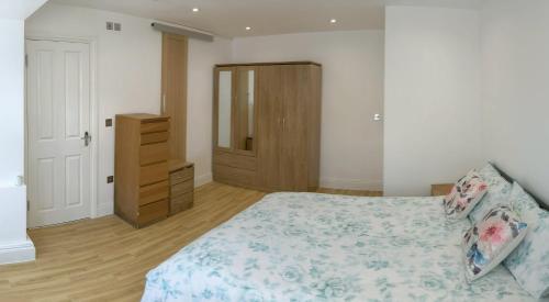 a bedroom with a bed and a wooden dresser at Spacious 2-bed apartment in central Kingston near Richmond Park in Kingston upon Thames