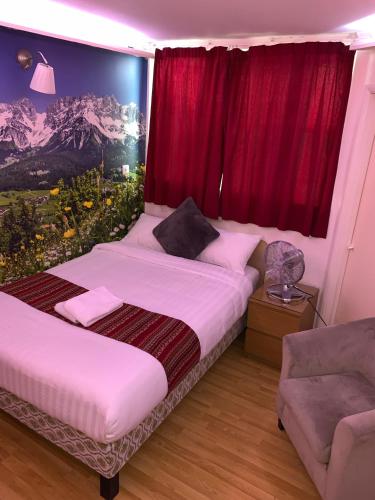 a bedroom with two beds and a window with red curtains at Barking Hotel in Barking