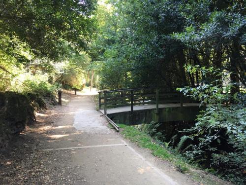 a bridge on a path next to a river with trees at Casas Á Beira - Apartamentos in Pontevedra