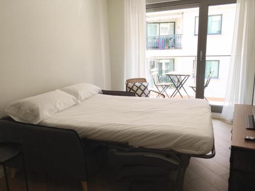 a bed in a room with a large window at Casas Á Beira - Apartamentos in Pontevedra