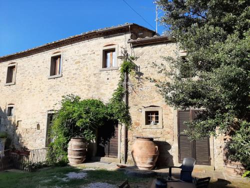 a stone house with a large vase in front of it at Agriturismo Frantoio Valiani in Cortona