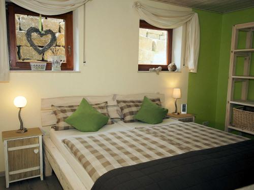 a bedroom with a bed with green walls and two windows at FeWo Die Dittrichs in Eggolsheim