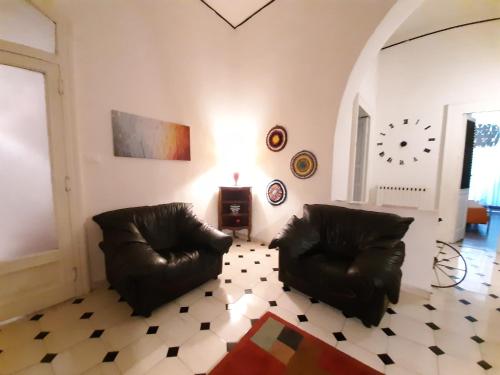a living room with two leather chairs and a clock on the wall at Casa Cenzina in Cosenza