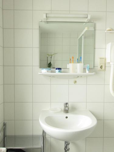 a white bathroom with a sink and a mirror at Uns Gartenhus mit Blick auf das Meer in Thiessow