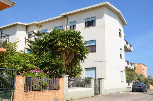 a white building with a palm tree in front of it at App.Violet Sardegna Mare La Caletta in La Caletta
